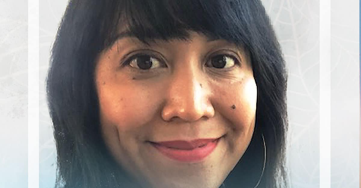 Close-up of a person with long black hair smiling softly, wearing red lipstick, reminiscent of a joyful kindergarten project. The background is light with subtle leaf patterns.